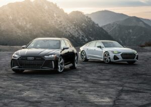 Two luxury Audi RS models parked on a scenic mountain road at sunset.
