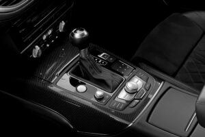 Close-up of a luxury car's gearshift and control panel, showcasing sleek design and detail.