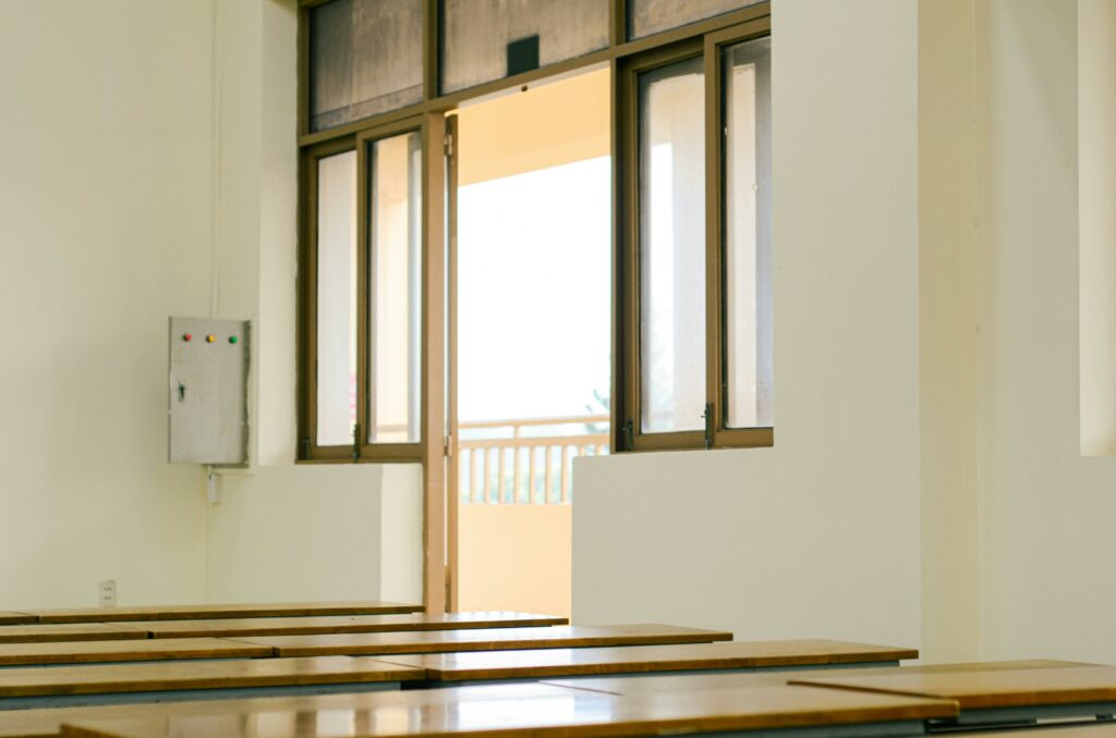 Sunlit classroom interior with open door and wooden desks, ideal for educational themes.
